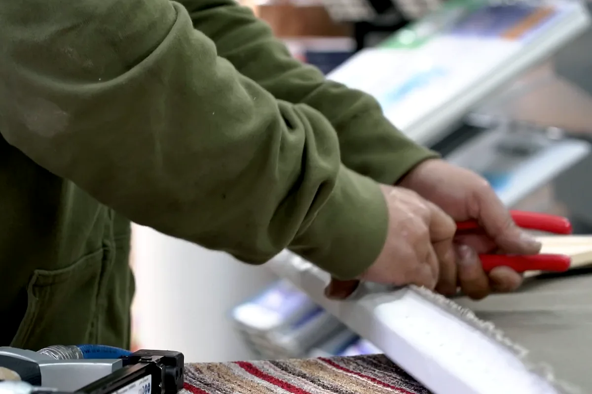 מתיחת שולי בד הקנבס מעל מסגרת העץ בעזרת צבת מתיחה ייעודית.